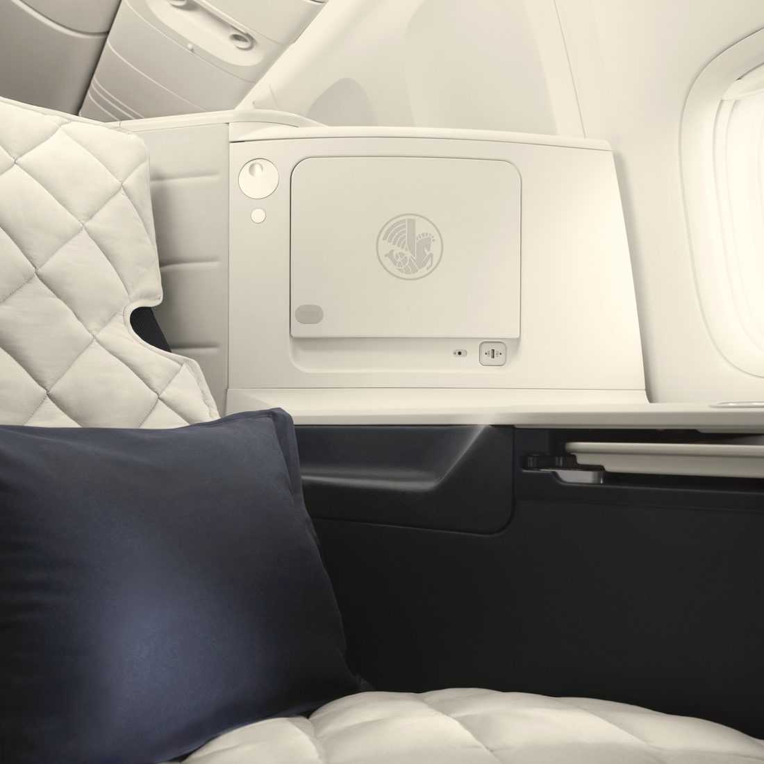 An Air France business class seat made up as a bed, navy pillow, window light