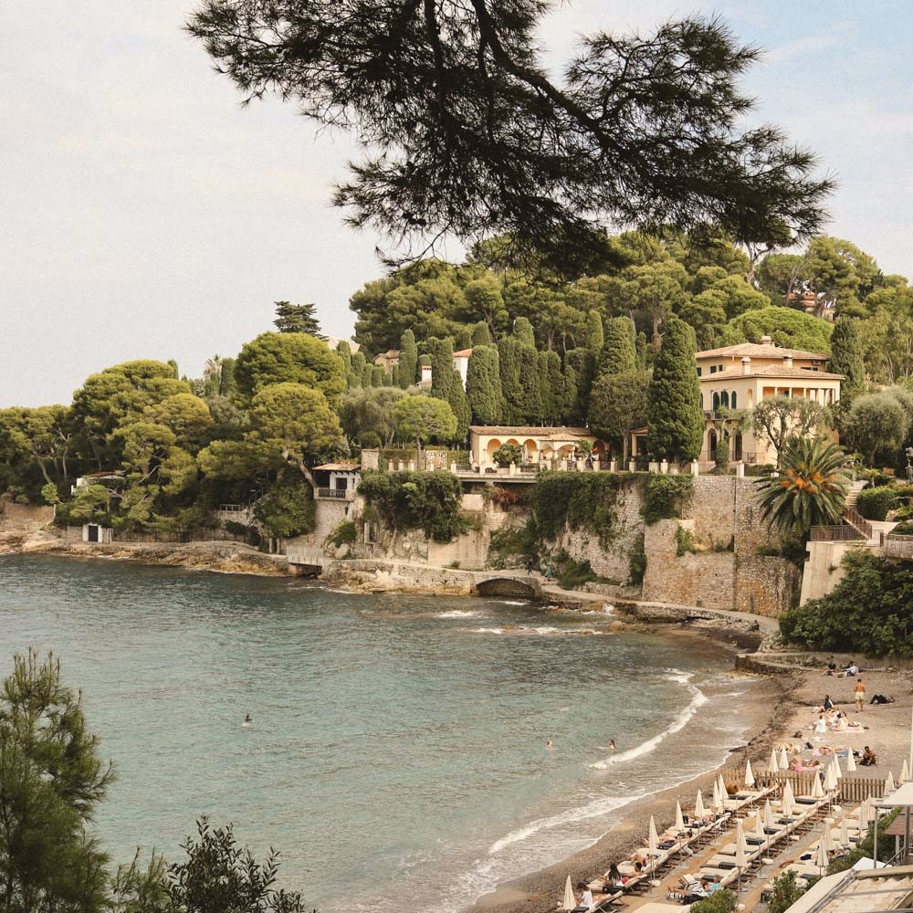 A sheltered cove on Cap Ferrat with pines, a villa above the water and a small beach